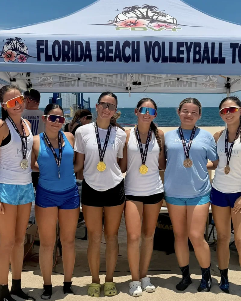 Six Mamu Beach athletes in club shirts wearing Florida Beach Volleyball Tour medals under the tour tent