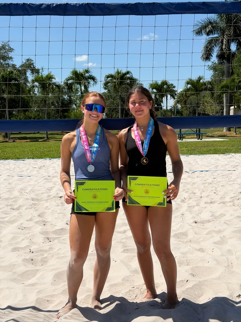 Two Mamu Beach athletes with gold and silver AVP Juniors medals, holding their 2026 national championship bid certificates